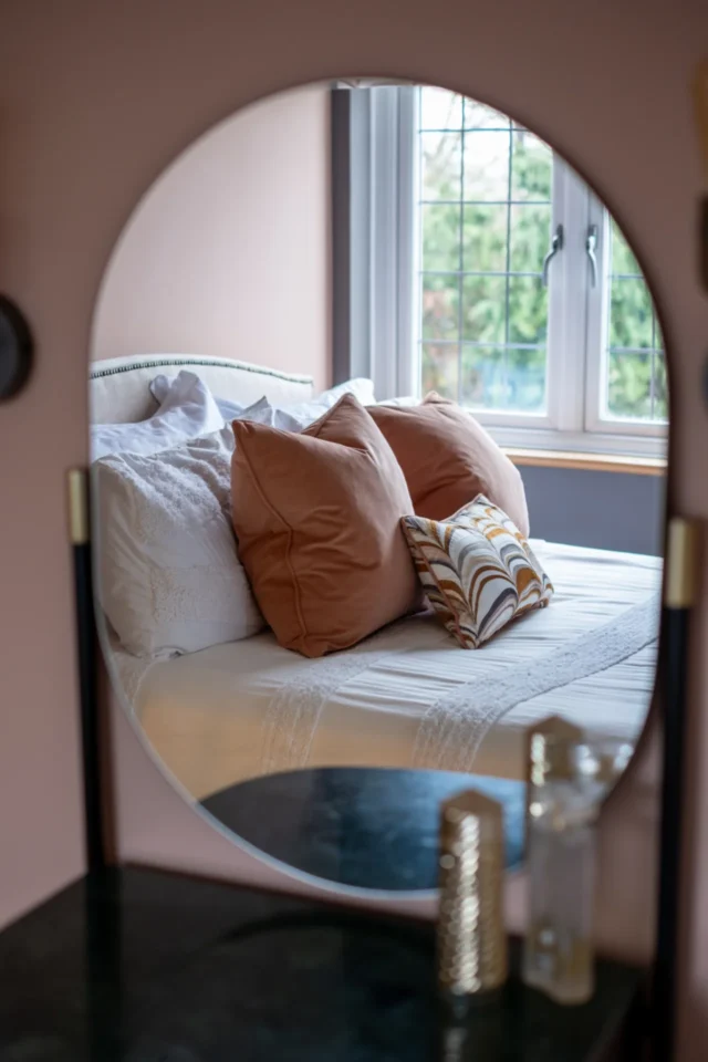 View of bed and cushions through dressing table mirror in eaves bedroom